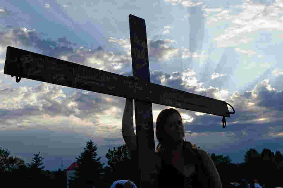 A woman holds a cross for the victims at the movie theatre Friday.