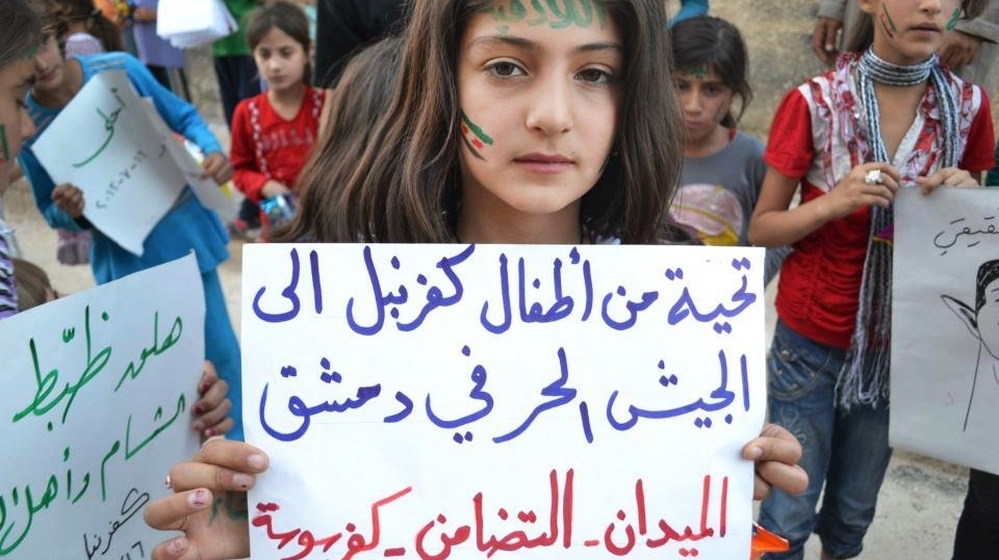 In this image taken July 16 and provided by Edlib News Network, a Syrian girl holds a poster that reads, "Greetings from Kfarnebel's children to the Free Syrian Army soldiers in Damascus," during a demonstration in Kfarnebel, Syria. Rebels hold large swaths of territory in rural Syria. Fighters in the village of Atima recently launched their first operation against the regime.
