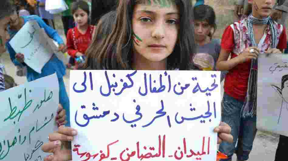 In this image taken July 16 and provided by Edlib News Network, a Syrian girl holds a poster that reads, "Greetings from Kfarnebel's children to the Free Syrian Army soldiers in Damascus," during a demonstration in Kfarnebel, Syria. Rebels hold large swaths of territory in rural Syria. Fighters in the village of Atima recently launched their first operation against the regime.