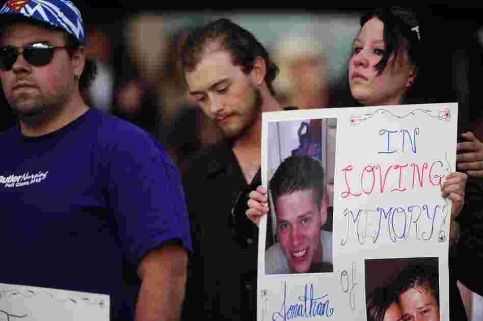 A sign is held in honor of Jonathan Blunk at a vigil in Aurora on Sunday. Blunk was one of the 12 killed in Friday's shooting.