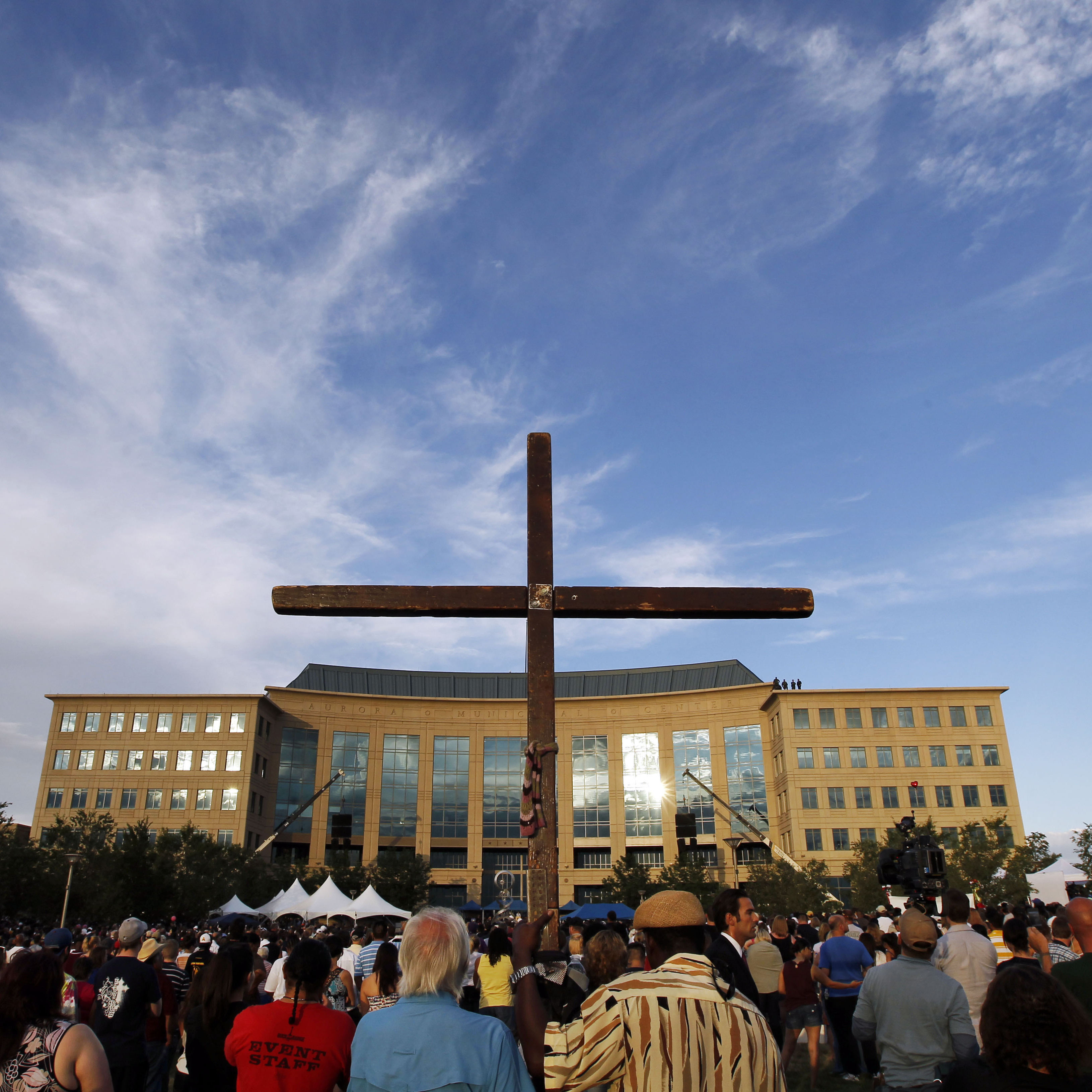 A cross stands among people gathered for the vigil at the Aurora Municipal Center Sunday.