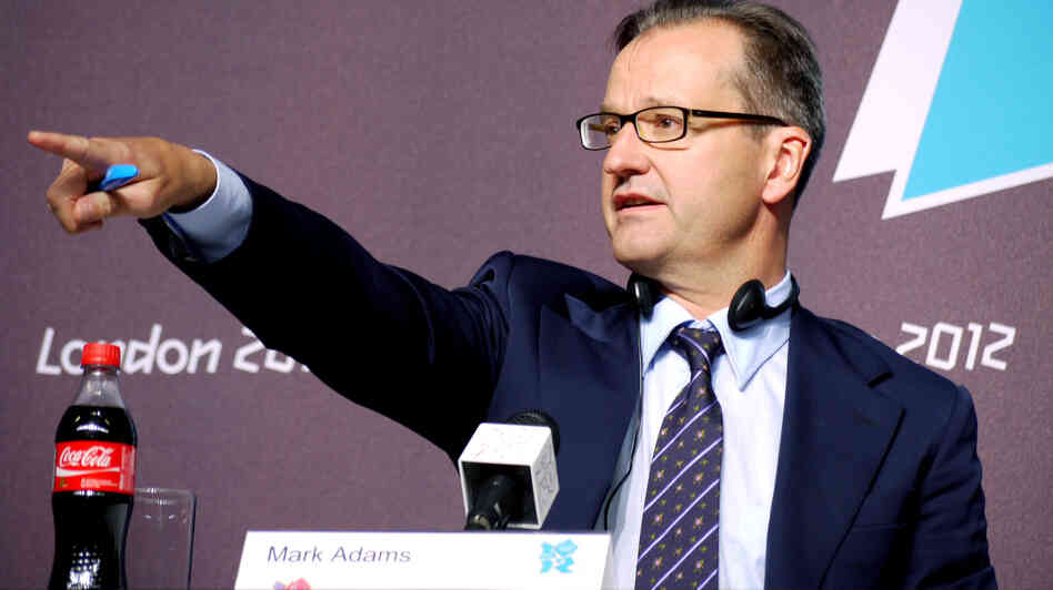 International Olympic Committee spokesman Mark Adams points to a reporter at a London news conference Saturday. The Olympic event may have been the first to have product placement.