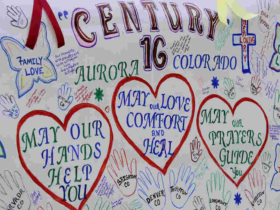 A banner with messages has been put up outside the theaters in Aurora, Colo., where 12 died and 58 were wounded early Friday.