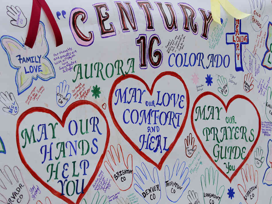 A banner with messages has been put up outside the theaters in Aurora, Colo., where 12 died and 58 were wounded early Friday.
