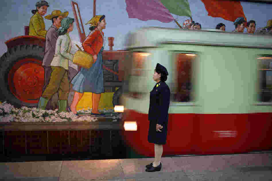 An attendant stands near the tracks as a metro train arrives in Pyongyang, North Korea, August 2007.