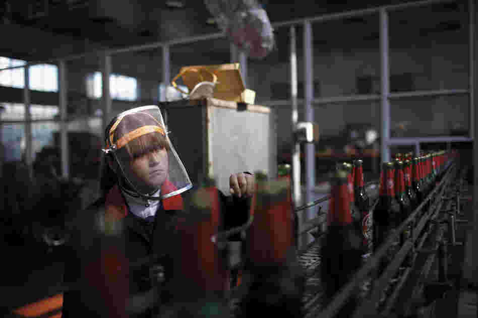 A worker inspects labels on beer bottles as they move down the production line at a brewery in Nanjie village, Henan province, China, November 2009. Nanjie is a collective village run along Maoist lines. Residents have socialist benefits like free education and health care, but there is no private property.