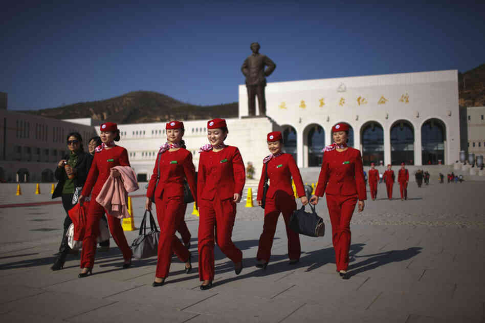 An all-girls group of Young Communist League members walks past a statue of Chairman Mao Zedong in Yan'an, China, November 2009. Yan'an is promoted as the "Revolutionary Holy Land" and offers a number of museums, monuments and other "Red Tourism" sites supported by the Chinese government.