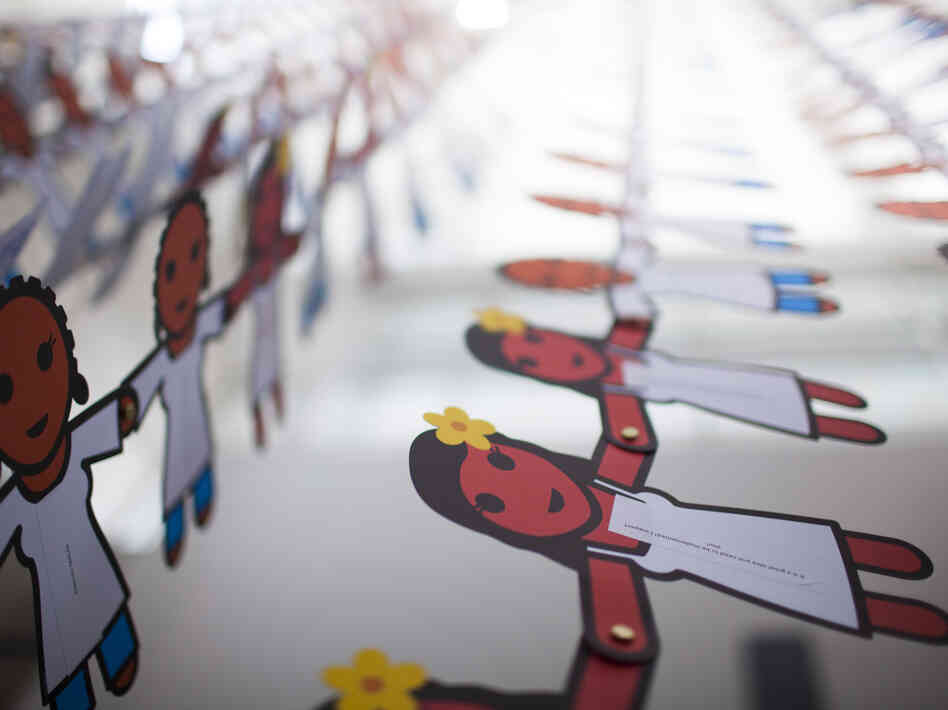A paper doll chain with more than 25,000 cutouts hangs from the ceiling of the Washington, D.C. convention hall. Each doll displays a message about the power of female condoms to stop HIV. A paper doll chain with more than 25,000 cutouts hangs from the ceiling of the Washington, D.C. convention hall. Each doll displays a message about the power of female condoms to stop HIV.
