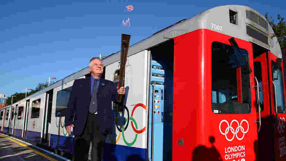 London Underground employee John Light (!) carries the Olympic torch onto a train at Wimbledon Station.