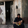 In this image provided by the Syrian opposition's Shaam News Network, a woman holds a child in front of their destroyed home in Tremseh, Syria, on July 14. The authenticity, content, location and date have not been independently verified.