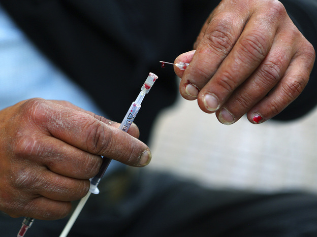 Vicky, a 40-year-old, Canadian-born, Greek drug addict, takes a drop of her own blood from a syringe as she prepares to inject herself with a mix of cocaine and heroin on a central Athens side street, April 30.