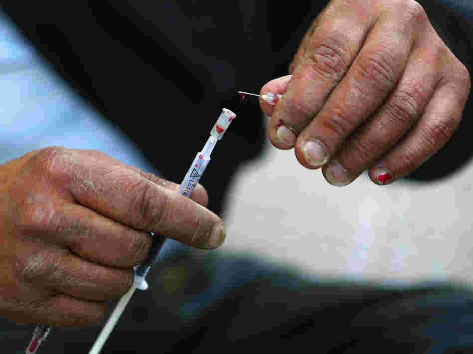 Vicky, a 40-year-old, Canadian-born, Greek drug addict, takes a drop of her own blood from a syringe as she prepares to inject herself with a mix of cocaine and heroin on a central Athens side street, April 30.