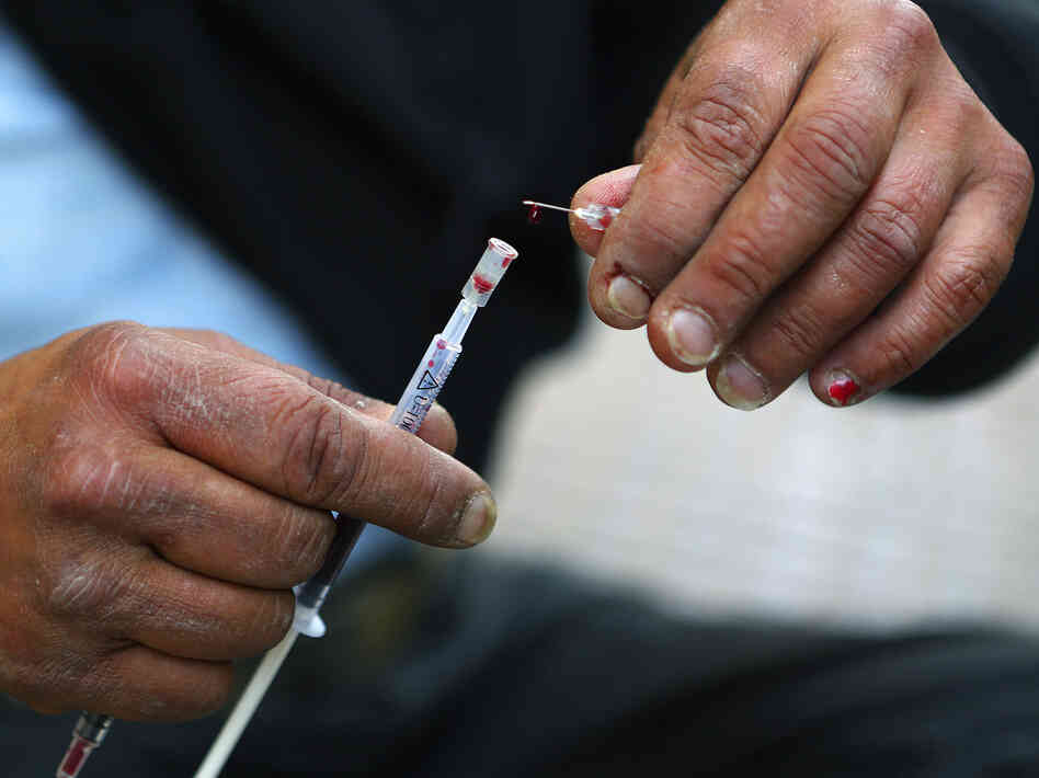 Vicky, a 40-year-old, Canadian-born, Greek drug addict, takes a drop of her own blood from a syringe as she prepares to inject herself with a mix of cocaine and heroin on a central Athens side street, April 30.