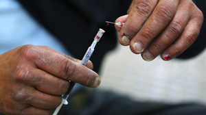 Vicky, a 40-year-old, Canadian-born, Greek drug addict, takes a drop of her own blood from a syringe as she prepares to inject herself with a mix of cocaine and heroin on a central Athens side street, April 30.
