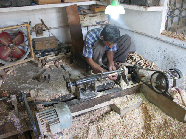 A lathe operator in the workshop of Halifax and Company turns out wood spindles that will be part of the pipes in toy bagpipes.
