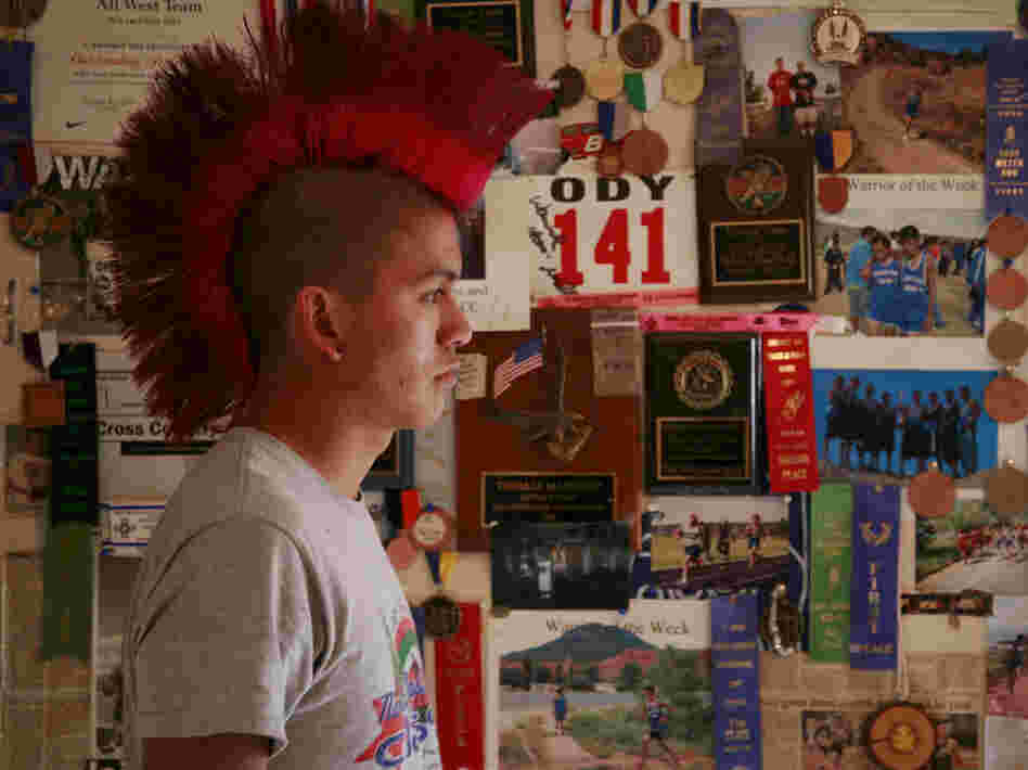 Thomas Martinez stands in front of "The Wall," an inspirational collection of his accolades, at his father's house.