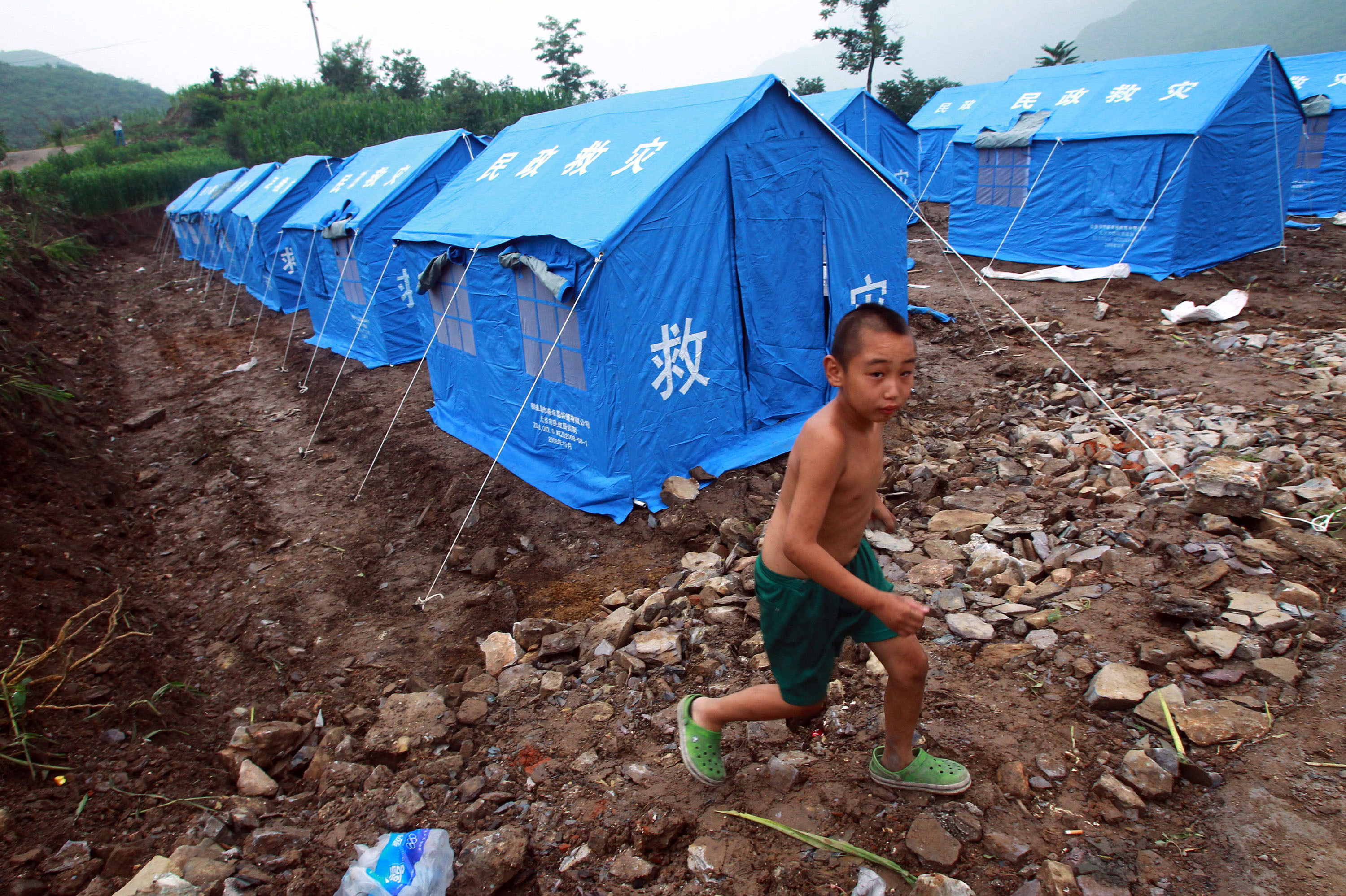 A young boy walks through a camp set up for victims of the flood in Beijing.