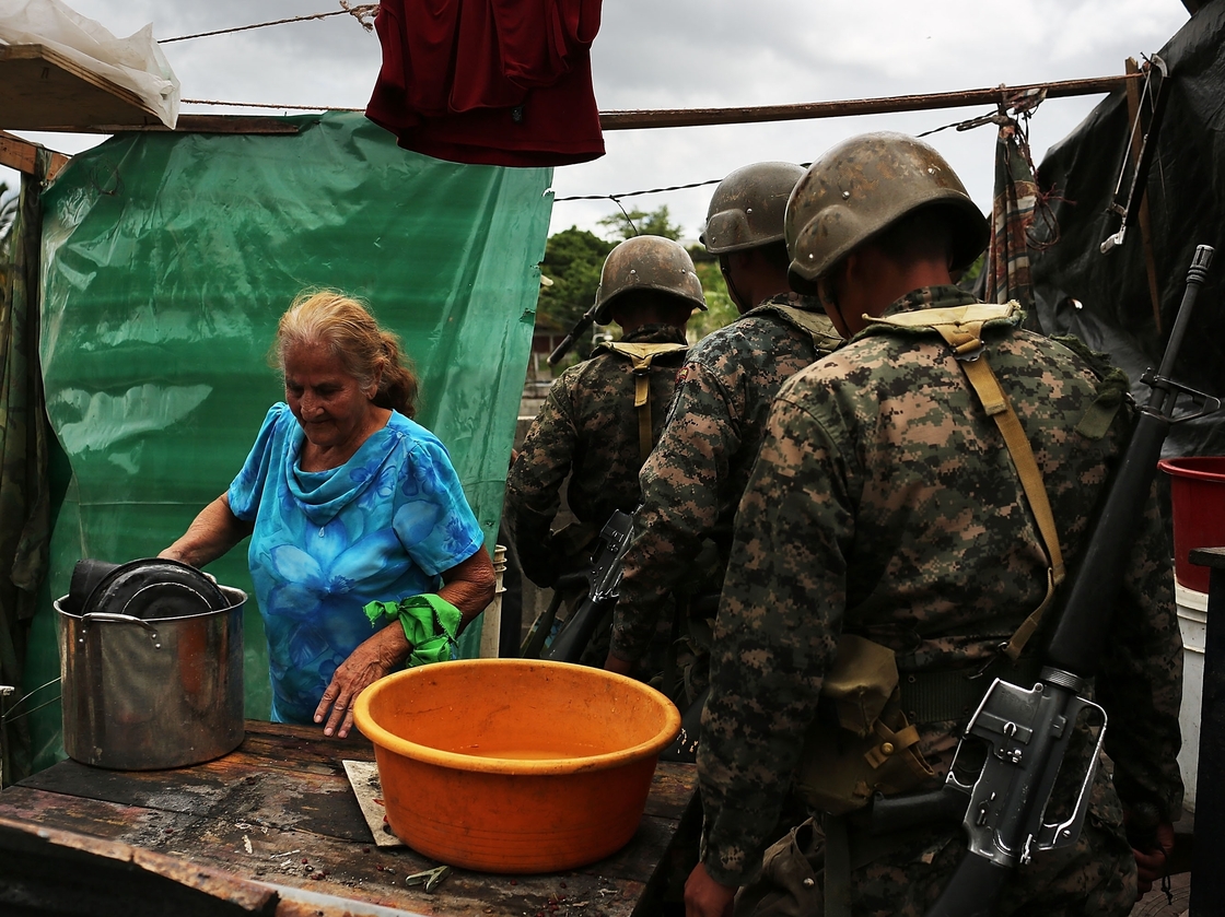An elderly woman dismantles her small shack as the military looks on after being forced to vacate following a government ruling that the settlement was illegal on July 20 in Tegucigalpa, Honduras. Land disputes are becoming more frequent in Honduras, which is alarming the nation's business class while sowing fears of increased political violence.