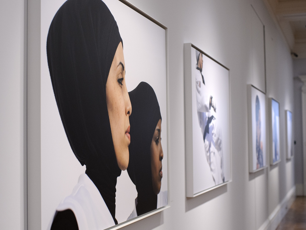 Photos hang at the opening of Hey'Ya Arab Women In Sport by Brigitte and Marian Lacombe at Sotheby's auction house in London.