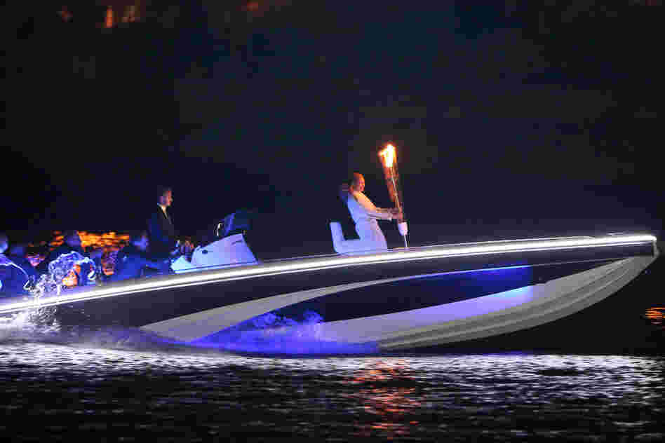 British soccer star David Beckham drives a speedboat carrying the Olympic flame to the opening ceremony.