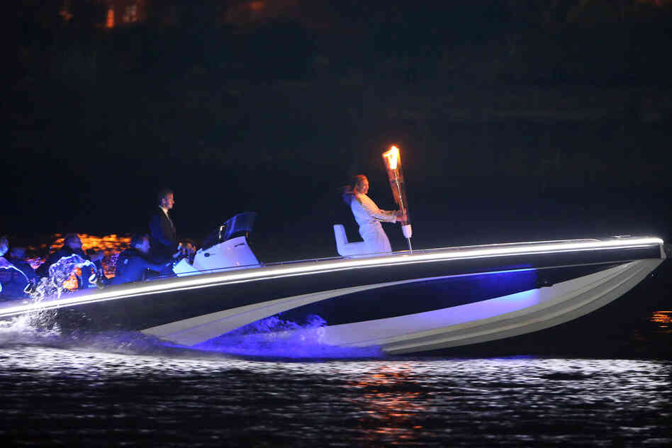 British soccer star David Beckham drives a speedboat carrying the Olympic flame to the opening ceremony.