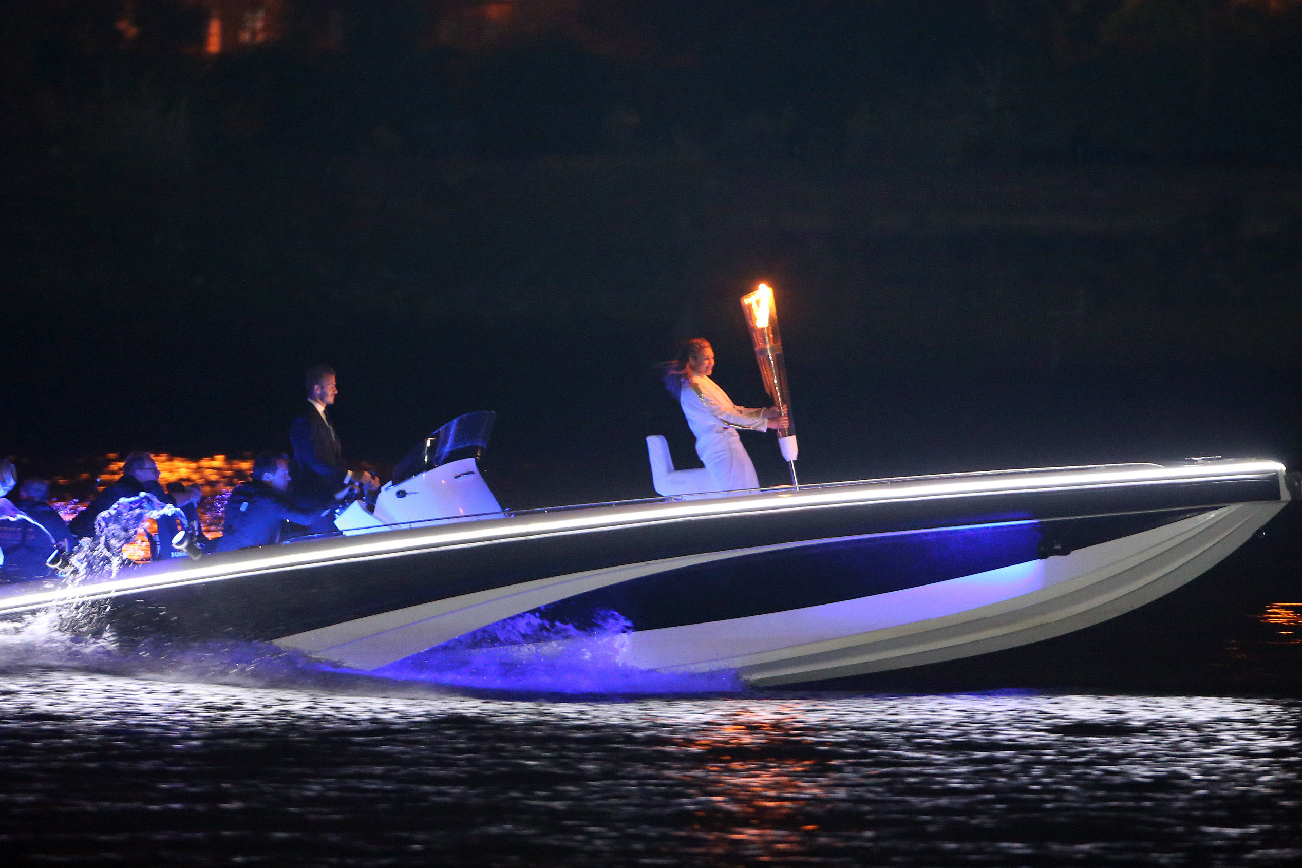 British soccer star David Beckham drives a speedboat carrying the Olympic flame to the opening ceremony.