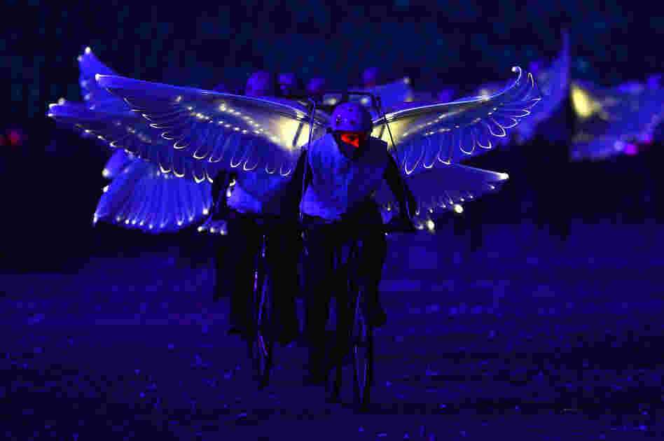 Winged performers ride bicycles during the opening ceremony.