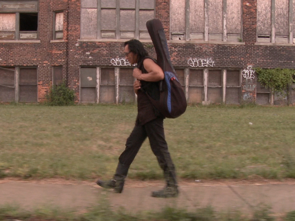 Rodriguez carries his guitar through Detroit, Mich., his hometown.