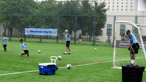 Aspiring soccer stars try to score against former Manchester City goalkeeper Alex Williams in Beijing. Local soccer clinics provide visiting international teams publicity for themselves and their sponsors.