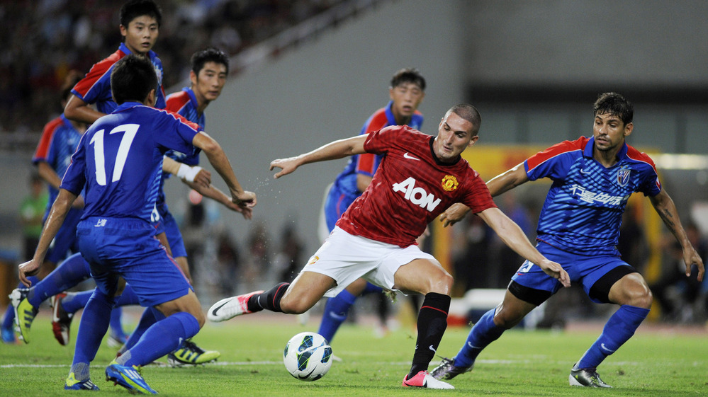 Federico Macheda of Manchester United (center) challenges players from Shanghai Shenhua during a friendly match between the two teams in Shanghai, China, on Wednesday.