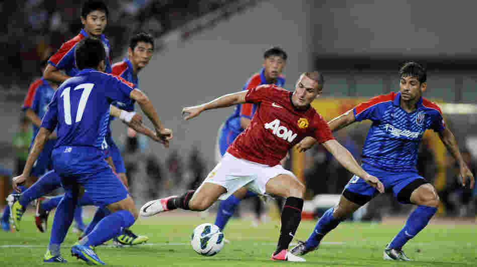 Federico Macheda of Manchester United (center) challenges players from Shanghai Shenhua during a friendly match between the two teams in Shanghai, China, on Wednesday.