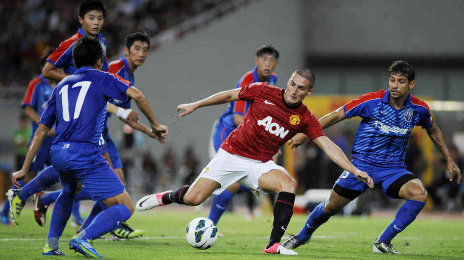 Federico Macheda of Manchester United (center) challenges players from Shanghai Shenhua during a friendly match between the two teams in Shanghai, China, on Wednesday.