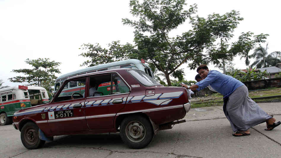An old taxi is pushed toward a vehicle license office to be exchanged for an import permit in Yangon, Myanmar. As many Burmese citizens take cars as an investment, many imports are sold and resold with a higher markup.