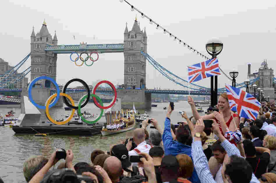 The Olympic torch is delivered by rowboat to the royal barge, Gloriana, on the River Thames, near Tower Bridge in London ahead of the opening ceremony Friday.