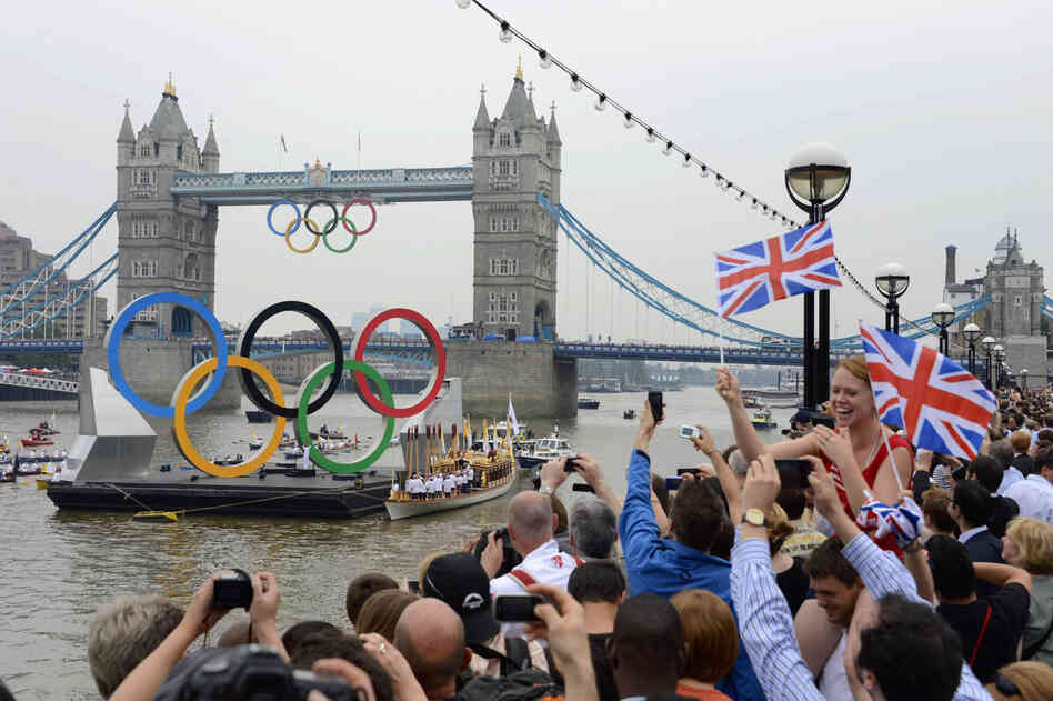 The Olympic torch is delivered by rowboat to the royal barge, Gloriana, on the River Thames, near Tower Bridge in London ahead of the opening ceremony Friday.