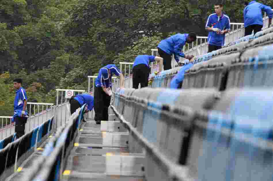 Volunteers wipe up water after a light rain at the equestrian stadium in Greenwich Park.
