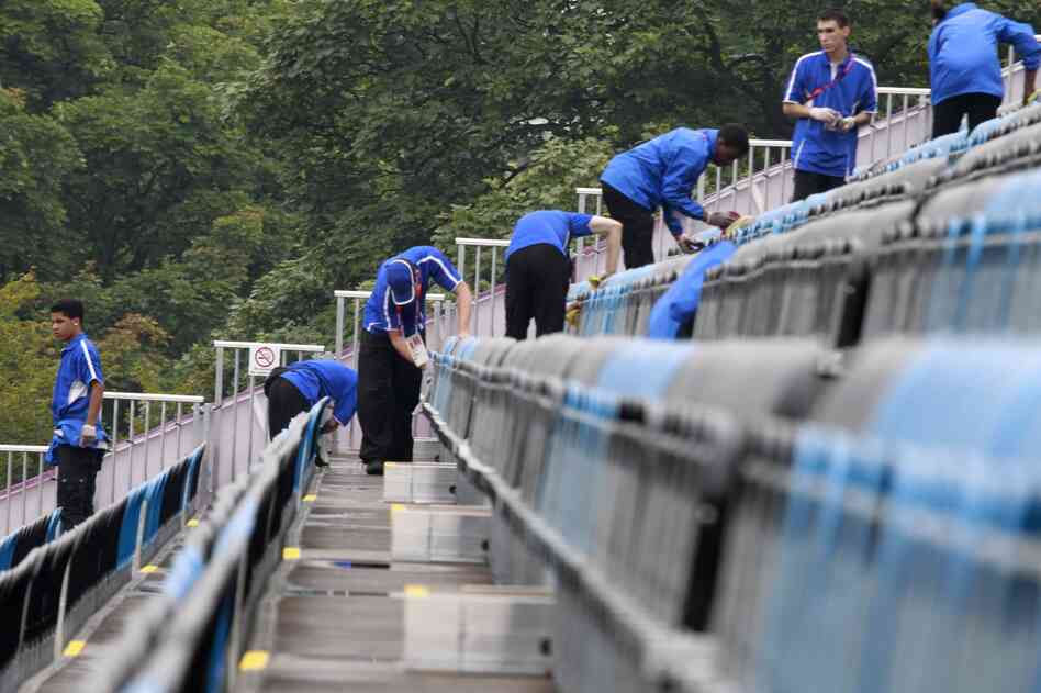 Volunteers wipe up water after a light rain at the equestrian stadium in Greenwich Park.