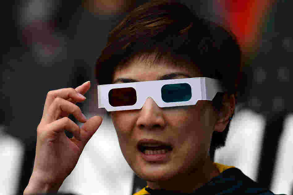 A fan wearing 3-D glasses watches the ceremony.