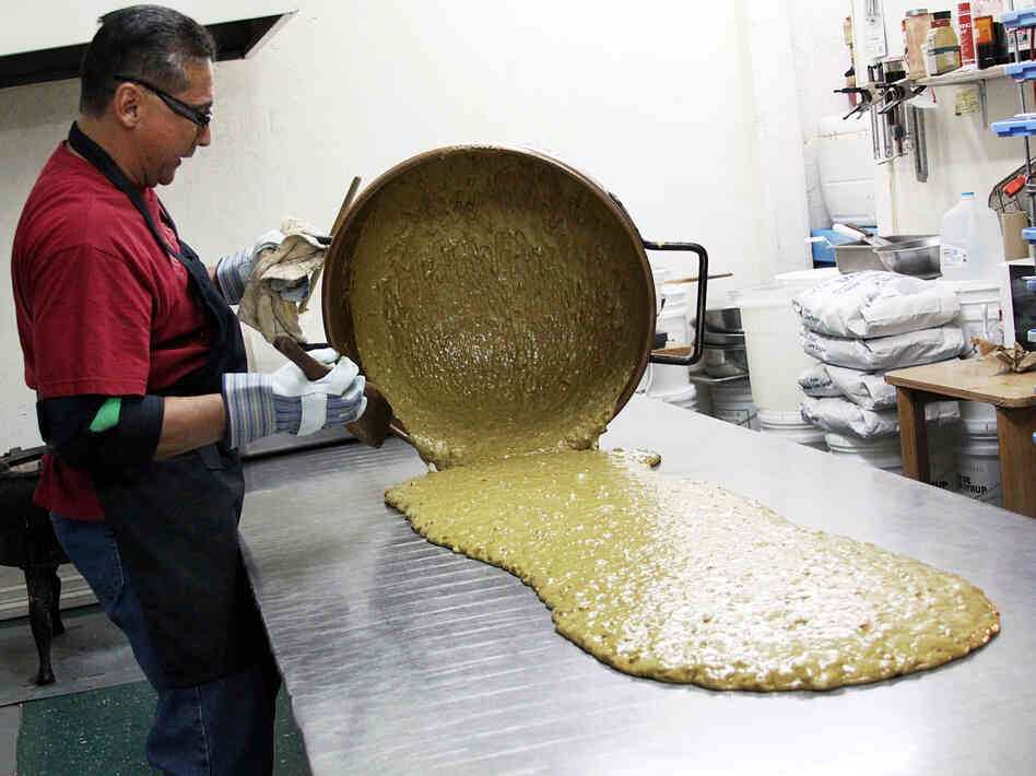 Las Cruces owner Luis Flores spreads out the hot mixture on a stainless steel table to cool and harden.