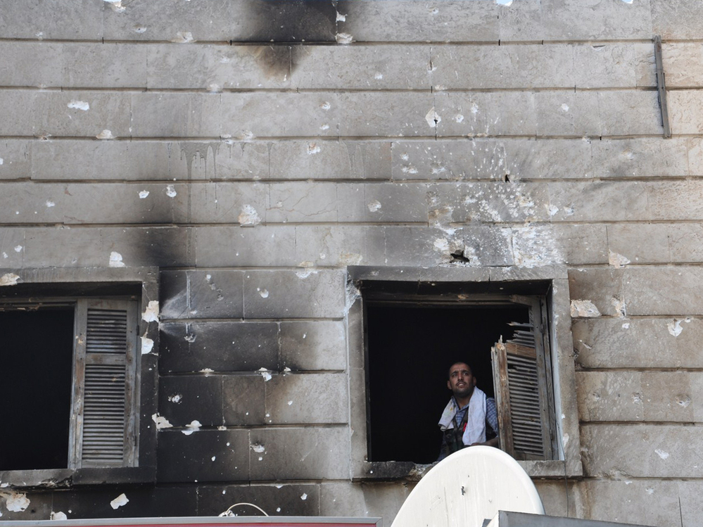 A Free Syrian Army fighter looks out from the window of a burnt-out police station in  Aleppo after it was overrun by rebel fighters last week.