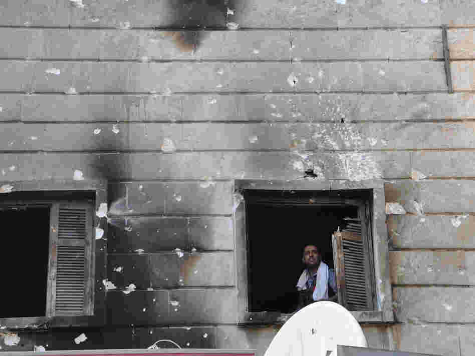 A Free Syrian Army fighter looks out from the window of a burnt-out police station in  Aleppo after it was overrun by rebel fighters last week.