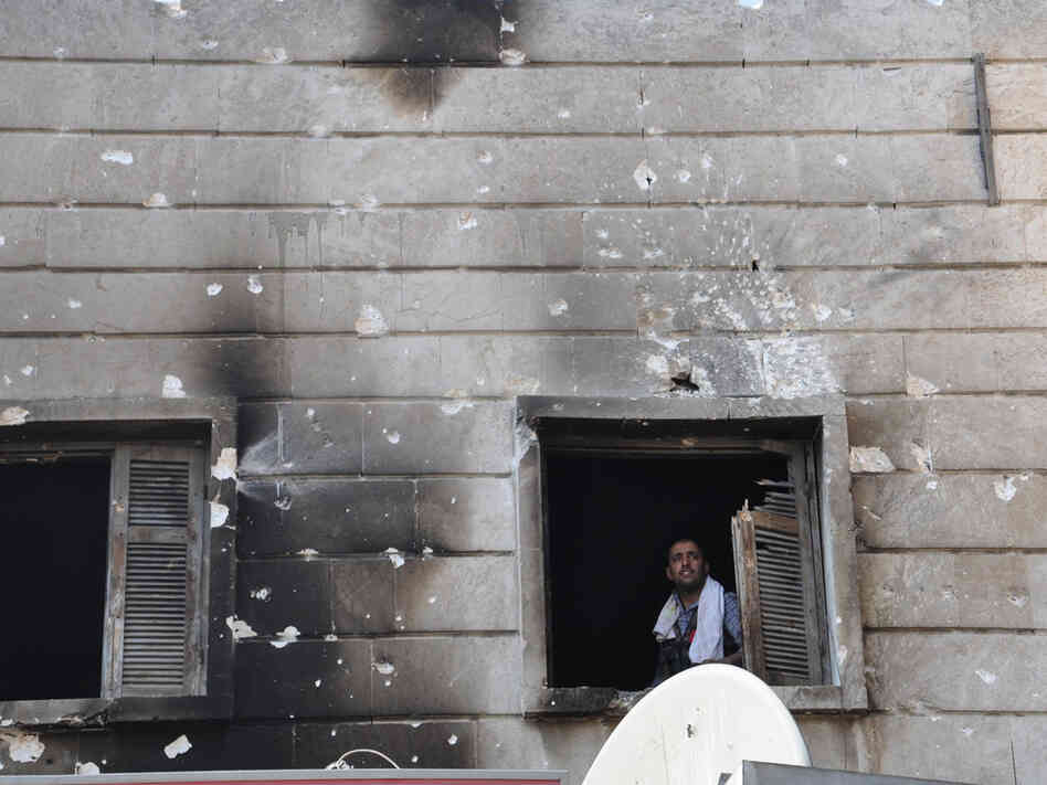 A Free Syrian Army fighter looks out from the window of a burnt-out police station in  Aleppo after it was overrun by rebel fighters last week.