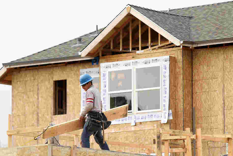 A construction worker carries lumber while working on new homes in San Mateo, Calif., in March. Homebuilding is at its highest level in nearly four years.