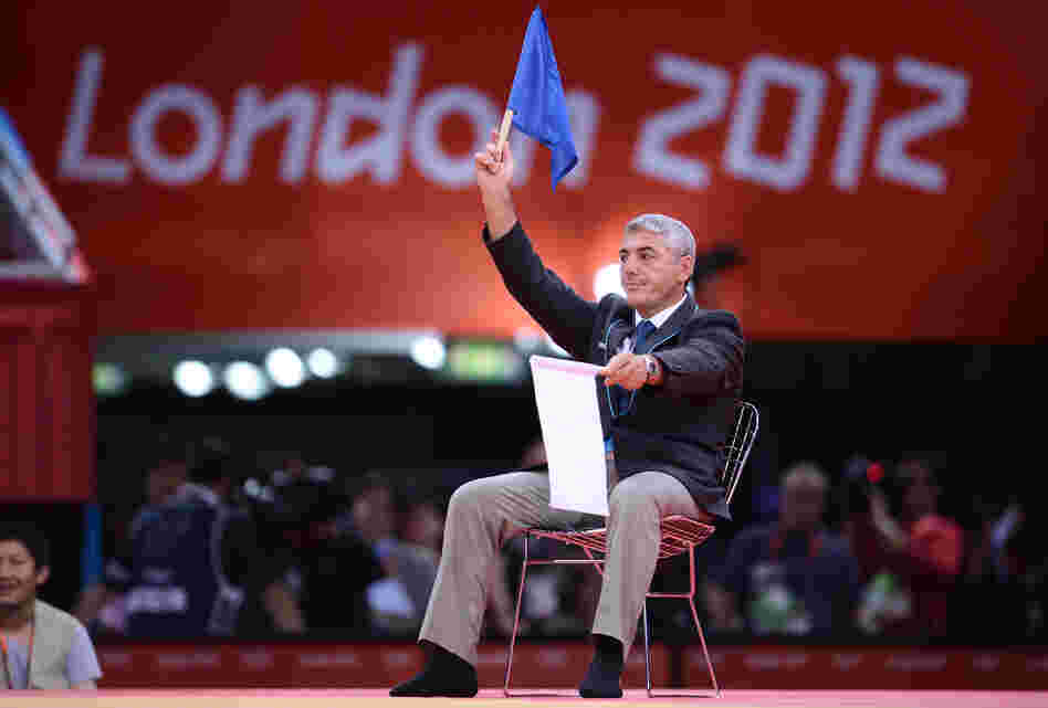 A judo judge waves a blue flag to award victory to South Korea's Cho Jun-Ho Sunday. But moments later, judges raised white flags instead, giving the win to Masashi Ebinuma of Japan.