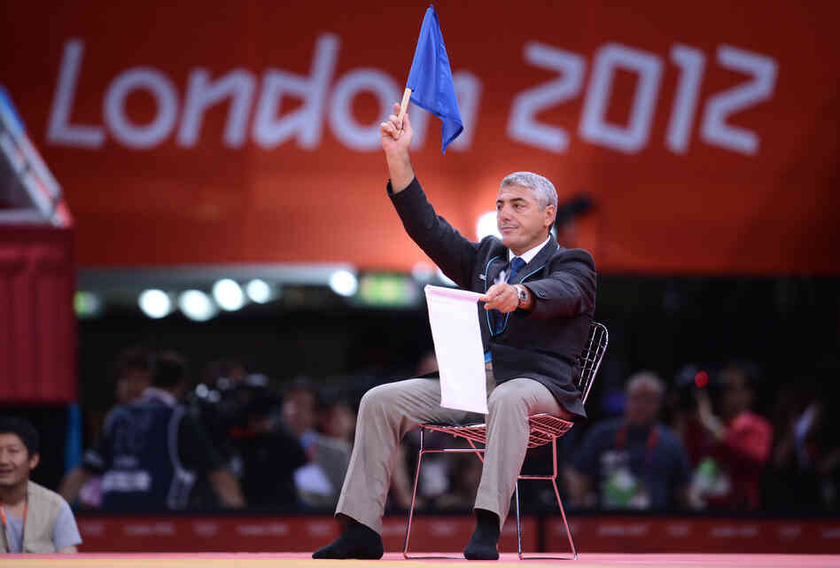 A judo judge waves a blue flag to award victory to South Korea's Cho Jun-Ho Sunday. But moments later, judges raised white flags instead, giving the win to Masashi Ebinuma of Japan.