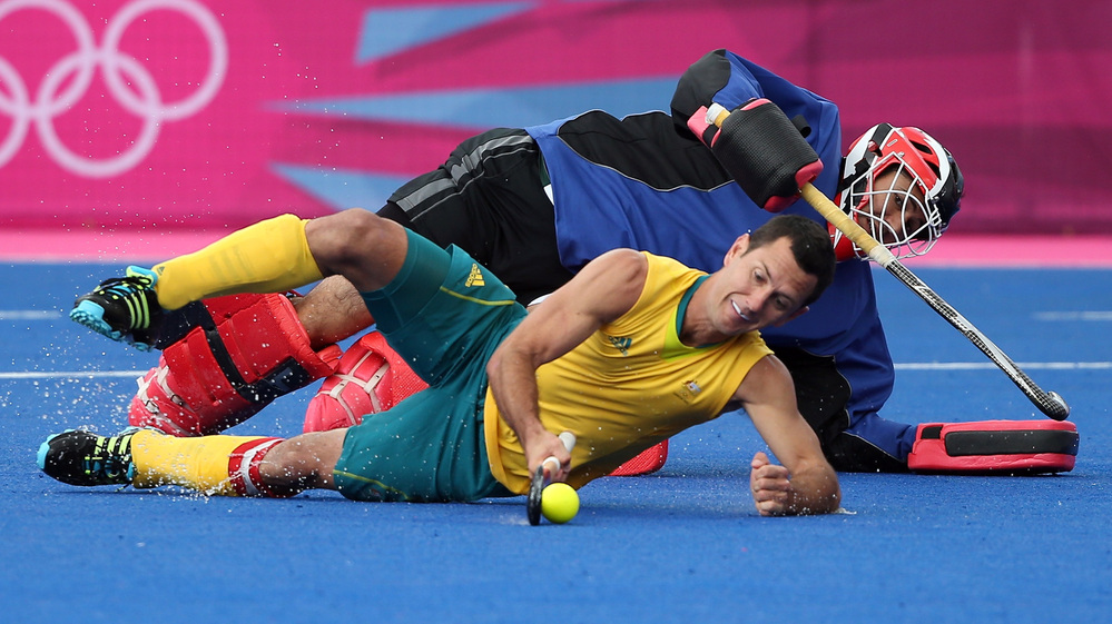 Australia's Jamie Dwyer, who scored three goals against South Africa in field hockey Monday, goes horizontal in London's Riverbank Arena. The South African goalie matched Dwyer's strategy, but Australia won, 6-0.