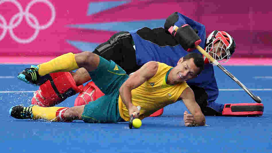 Australia's Jamie Dwyer, who scored three goals against South Africa in field hockey Monday, goes horizontal in London's Riverbank Arena. The South African goalie matched Dwyer's strategy, but Australia won, 6-0.