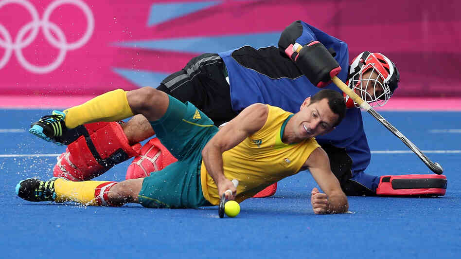 Australia's Jamie Dwyer, who scored three goals against South Africa in field hockey Monday, goes horizontal in London's Riverbank Arena. The South African goalie matched Dwyer's strategy, but Australia won, 6-0.