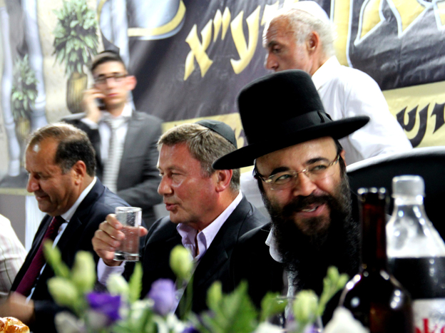 Ifargan, right, sits next to businessman Nochi Dankner, center, at an annual gala in Netivot, Israel, that honors the rabbi.