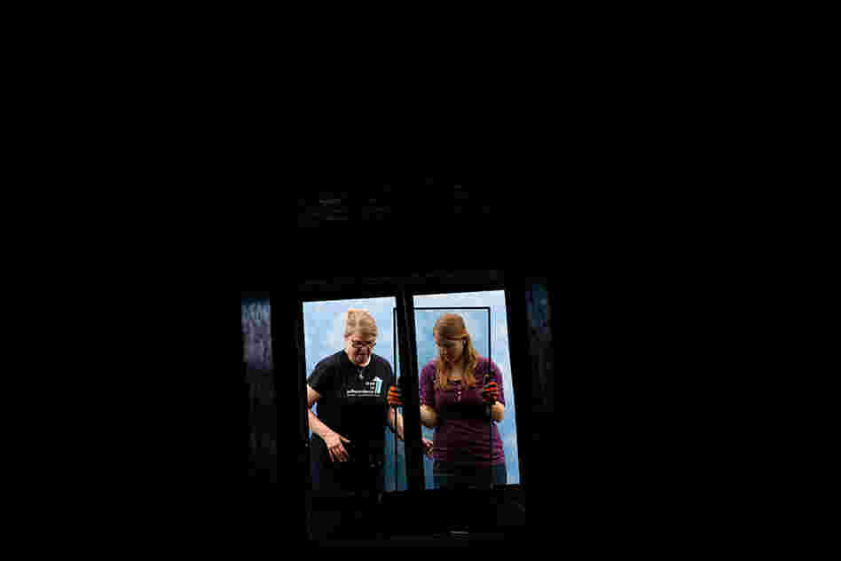 Christine Sheppard (left), an ornithologist with the American Bird Conservancy, and her assistant, Cara Menzel, insert two panes of glass into a test tunnel. One pane is a regular piece of glass; the other has a pattern of lines painted on the inside that reflects ultraviolet light. The birds can see the pattern, but it is barely detectable by the human eye.